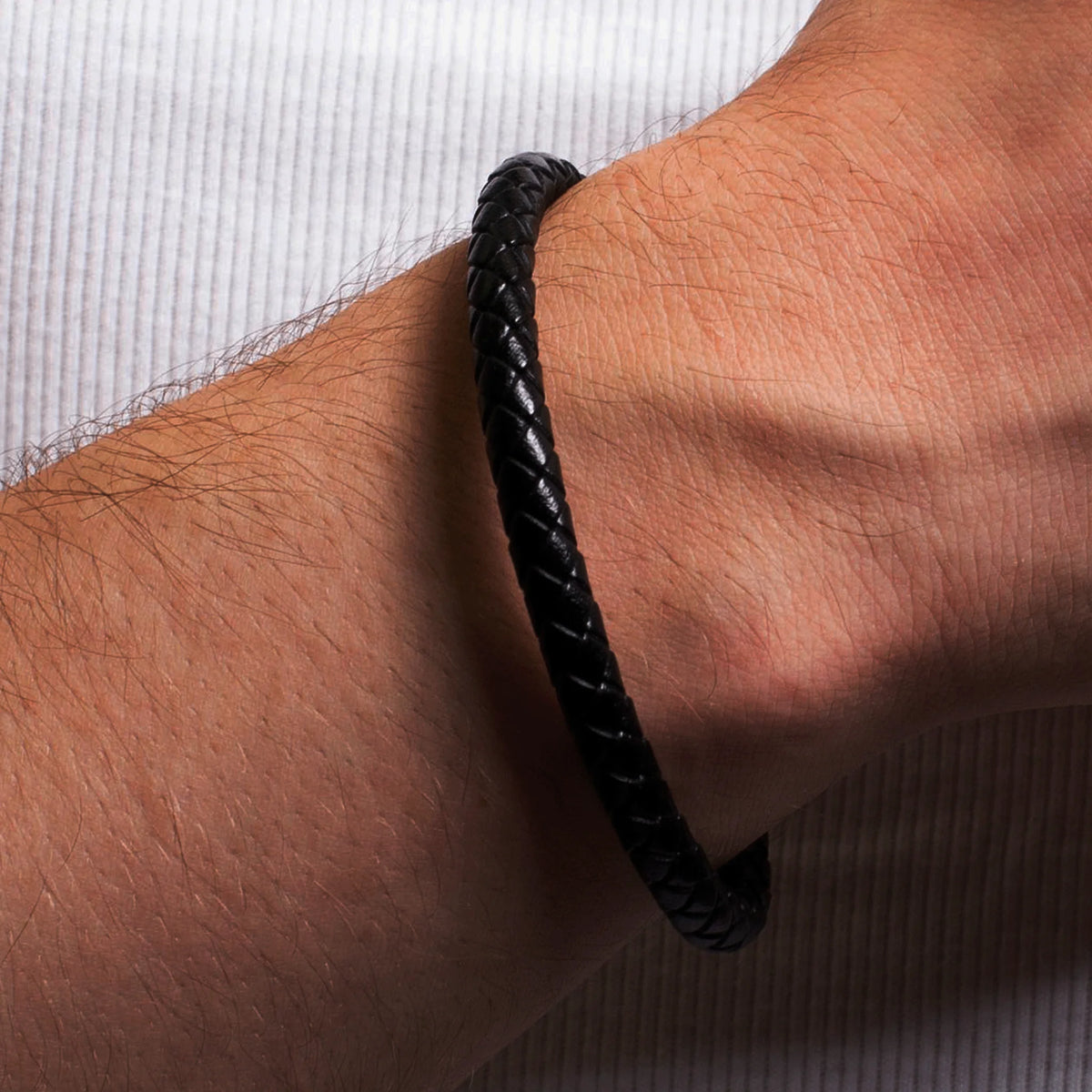 Black braided leather bracelet worn on a wrist.