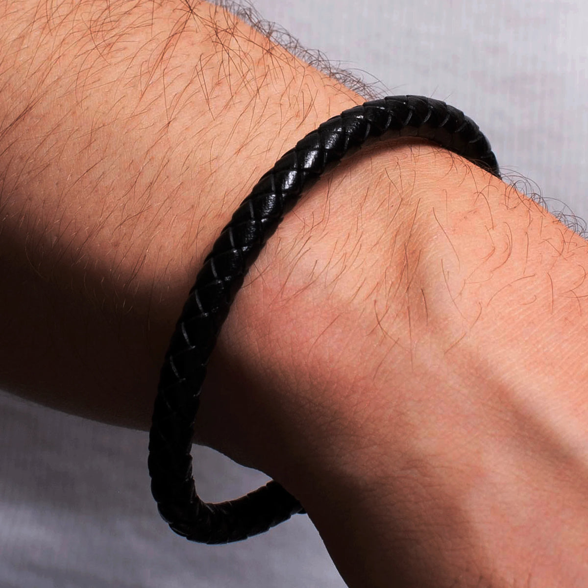 Black braided leather bracelet worn on a wrist.