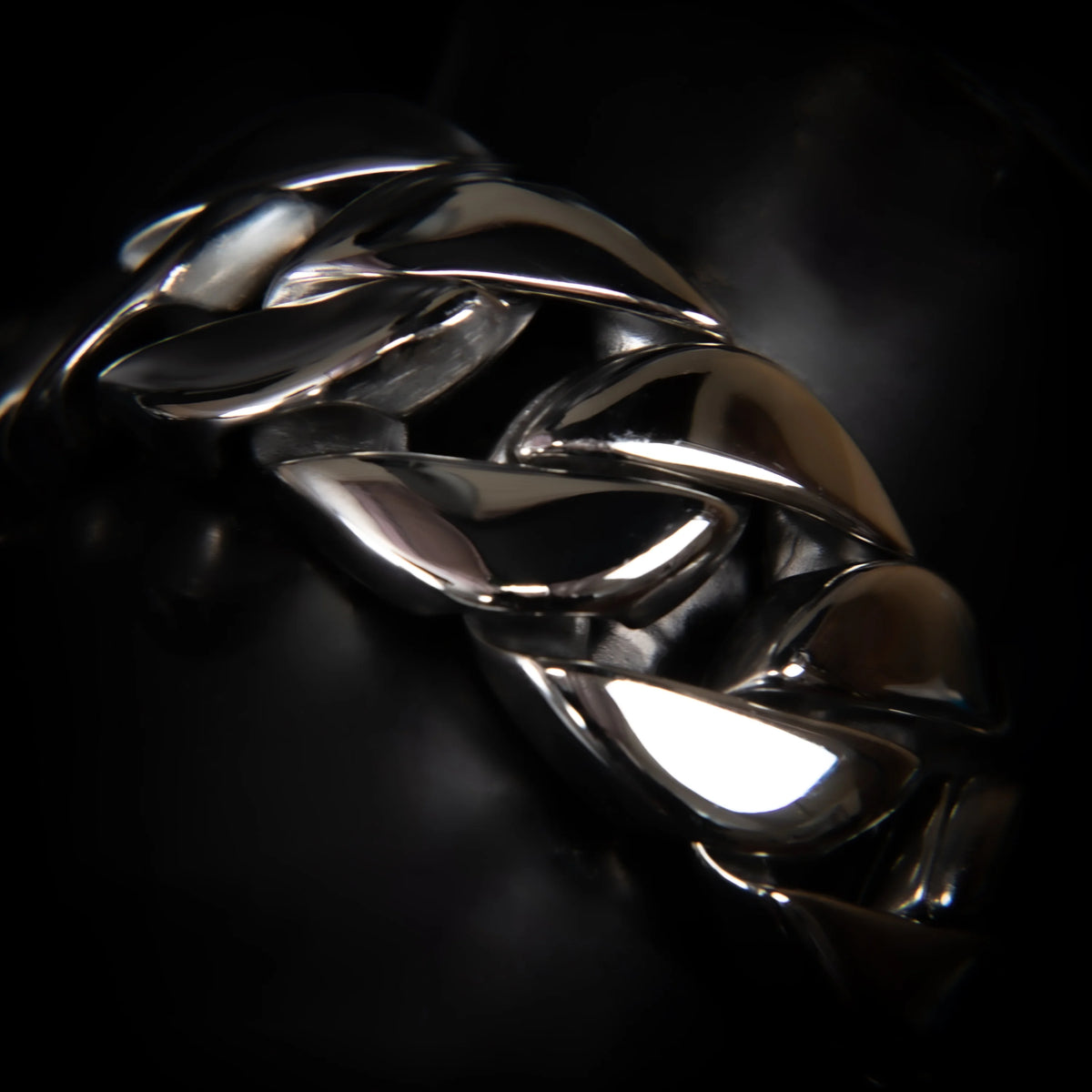 Shiny metallic bracelet or chain with interlocking leaf-like shapes.