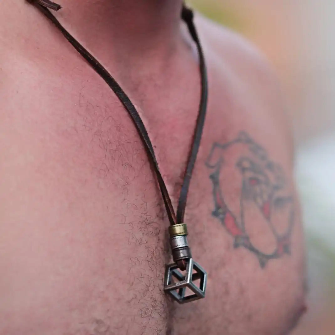 Geometric cube-shaped pendant hanging from a leather cord necklace.