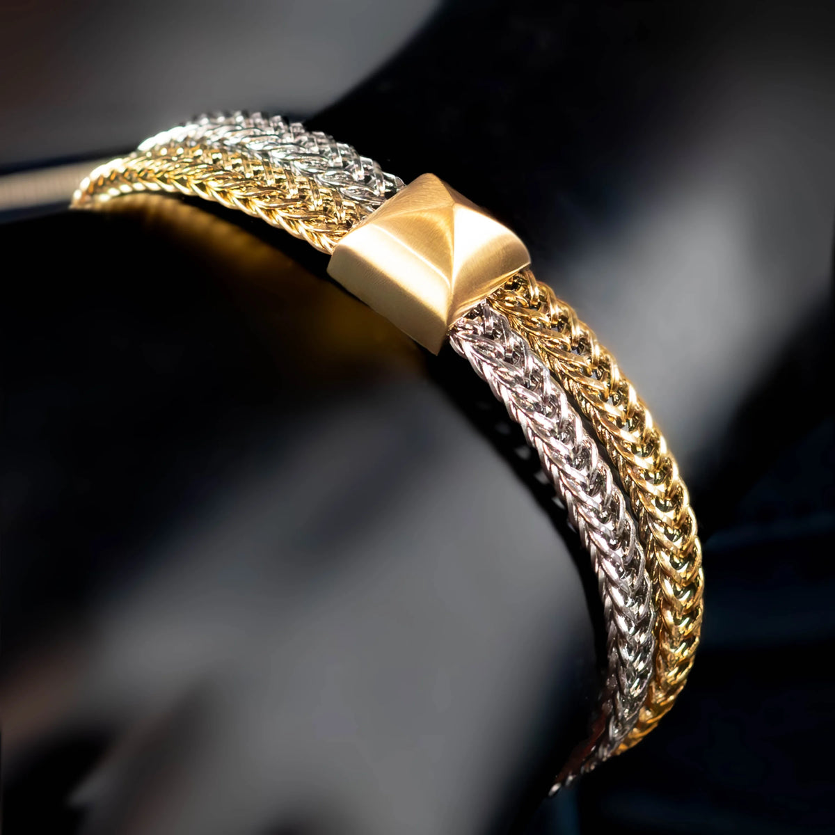 Two-tone braided bracelet with a gold pyramid-shaped centerpiece.