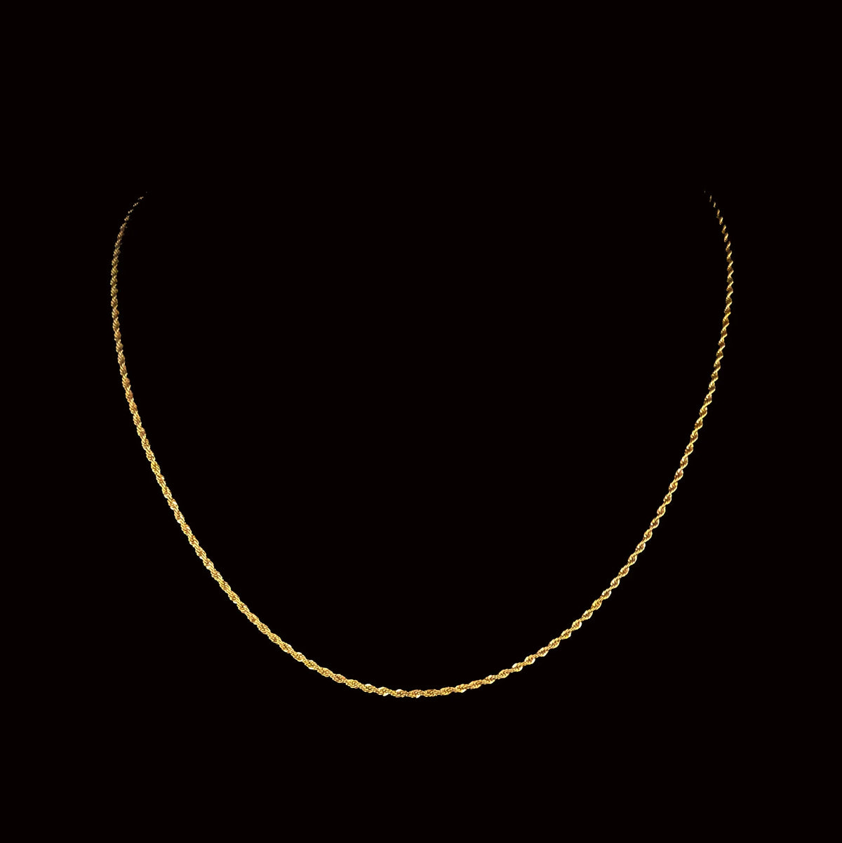 Gold rope chain necklace against a dark background.