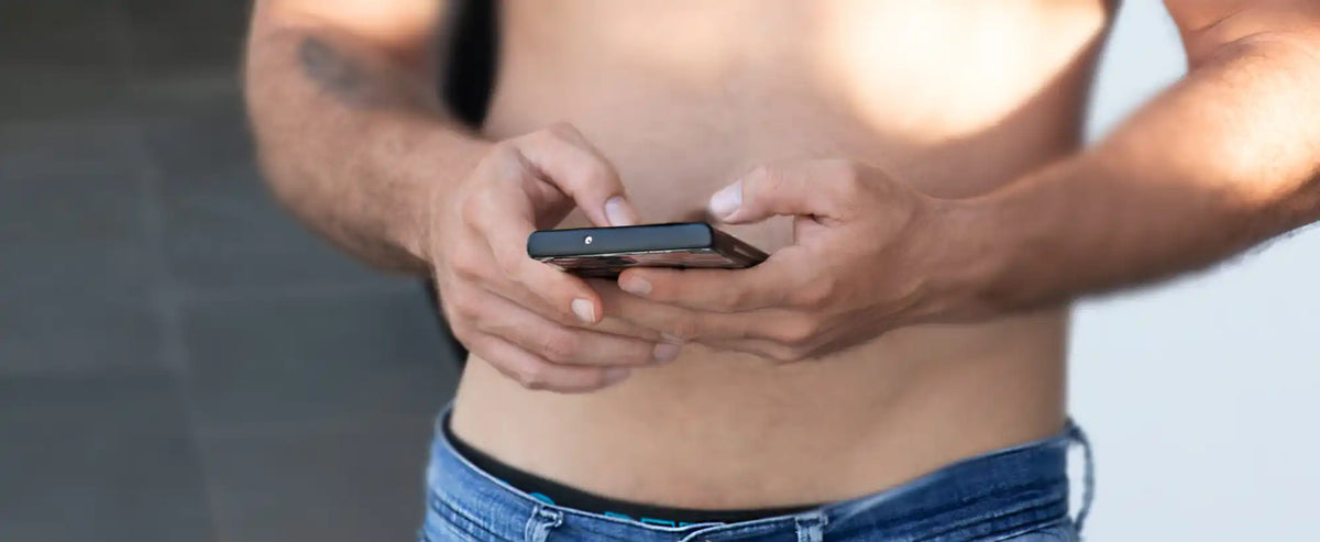 Handheld black mobile phone being held in both hands.