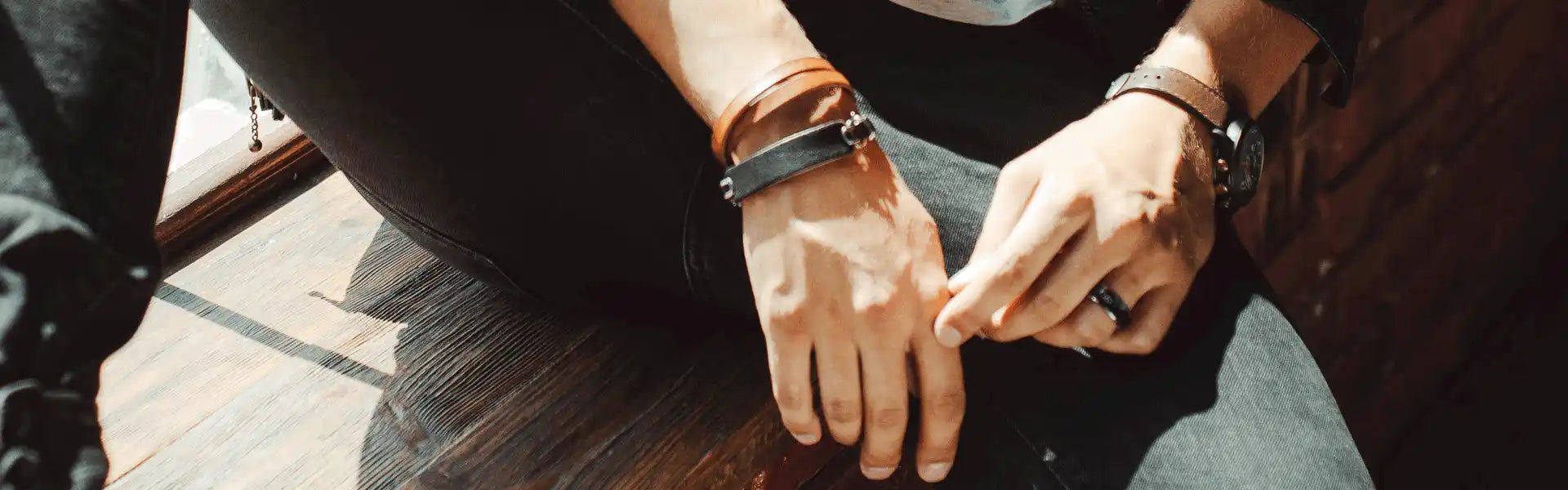 Hands wearing a brown leather watch and bracelet.