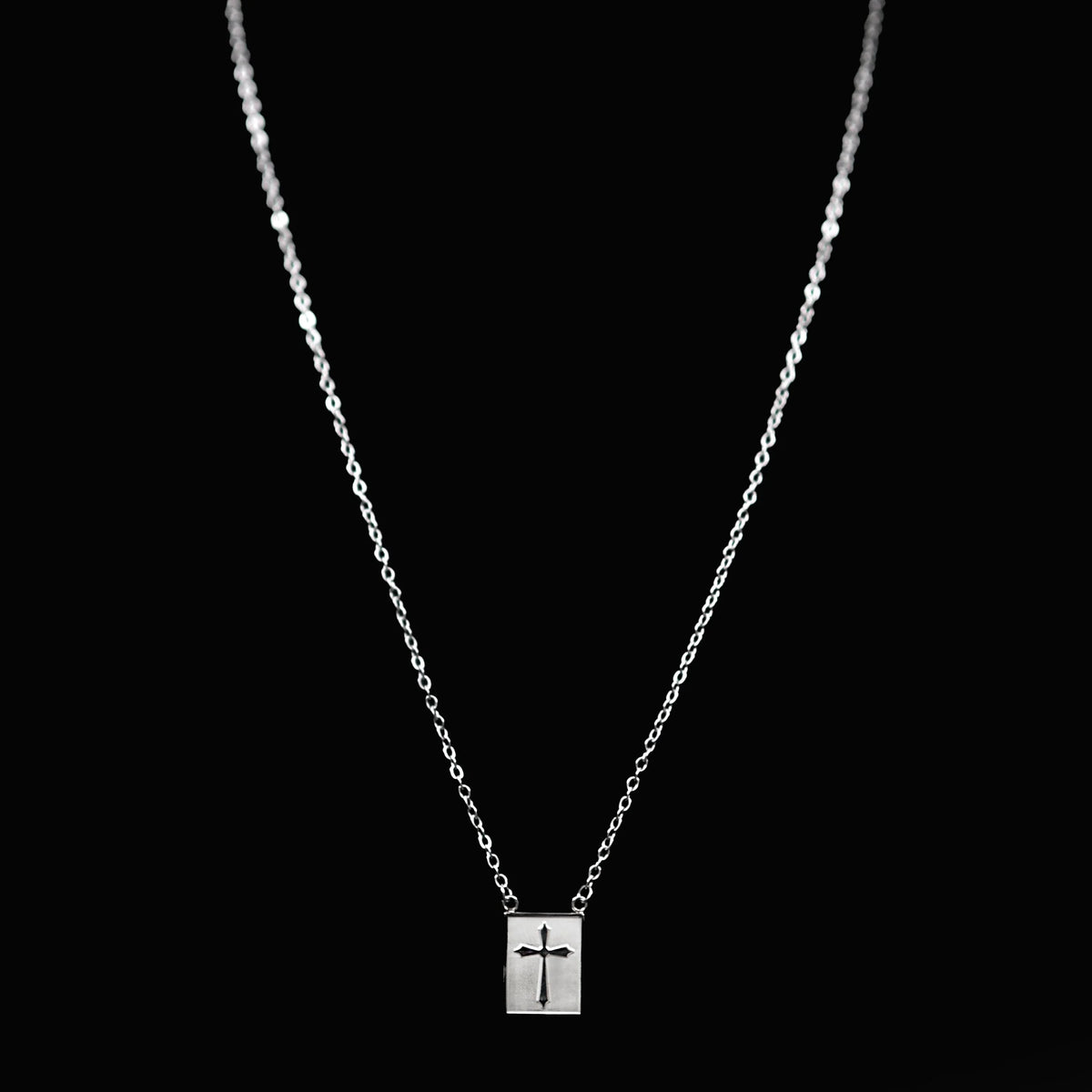 Silver necklace with a rectangular pendant featuring a cross design.