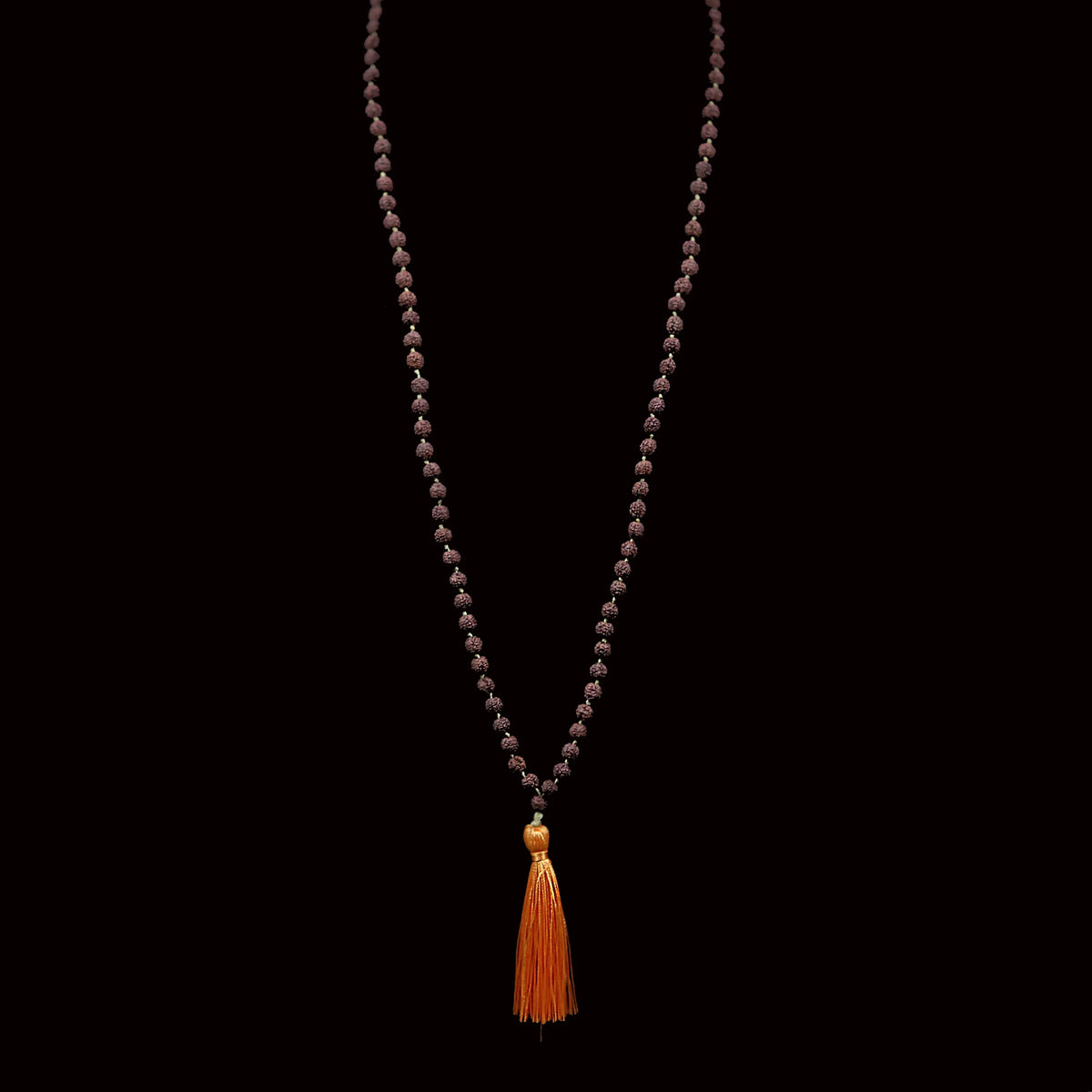 Beaded necklace with an orange tassel pendant.