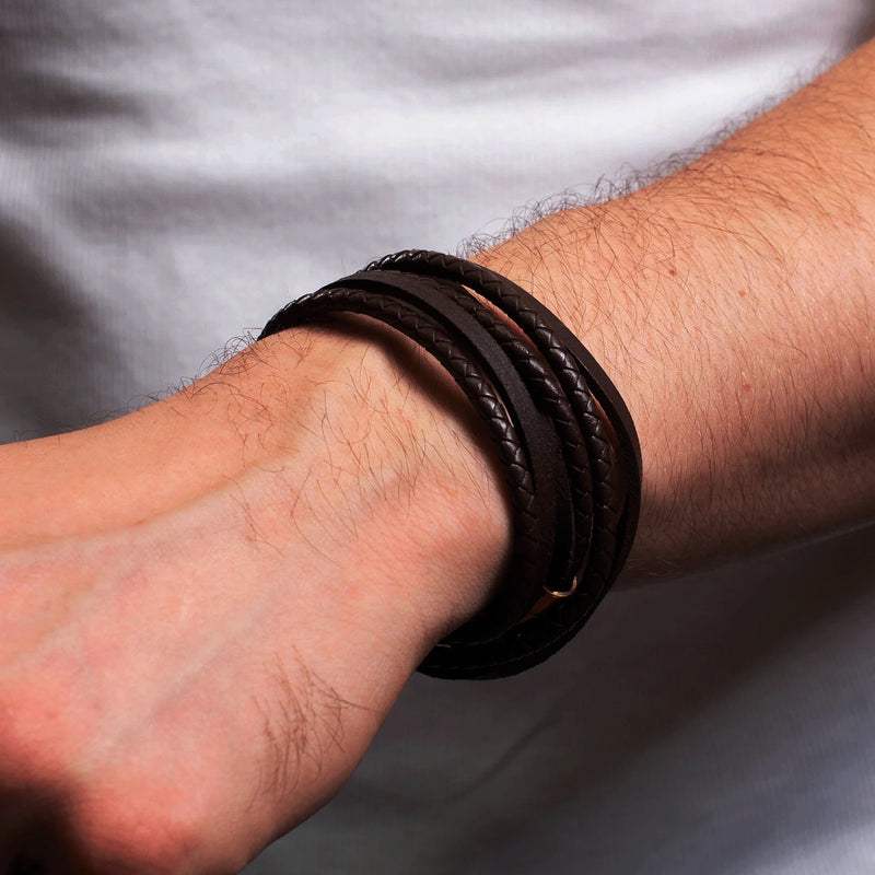 Dark leather bracelet with multiple strands worn on a wrist.