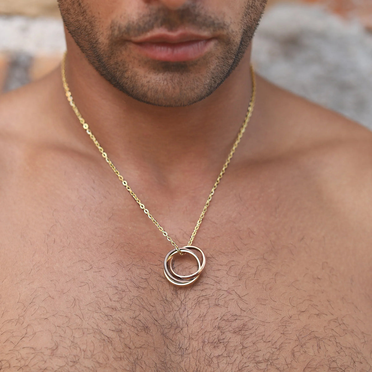 Gold chain necklace with interlocking circular pendant.