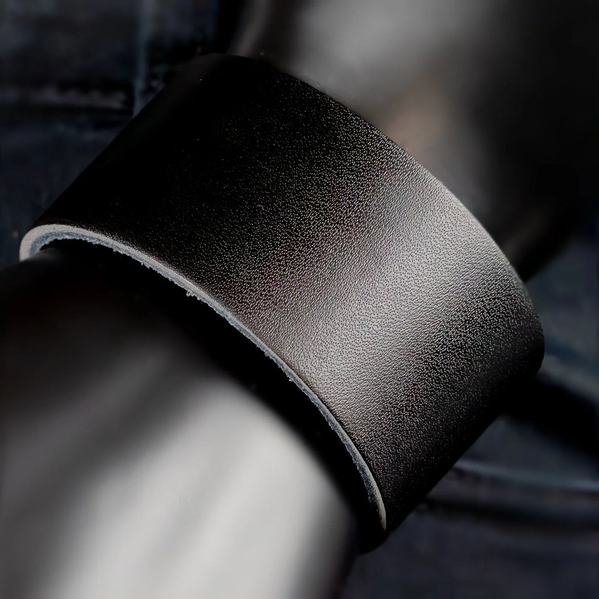 Curved piece of black leather with a textured surface.