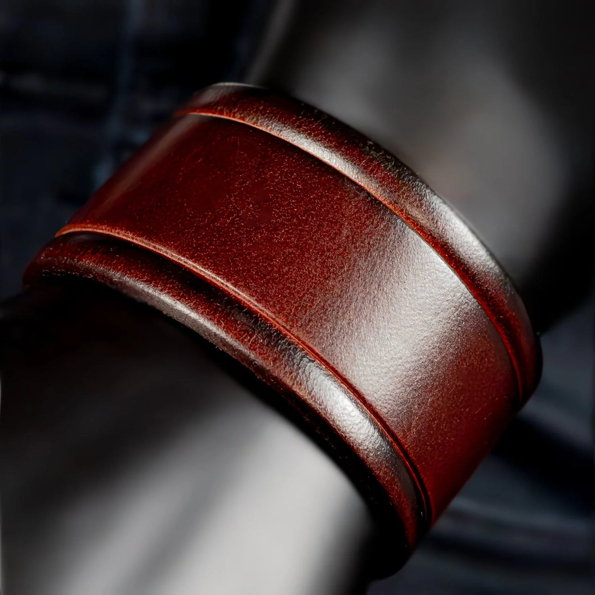 Rich burgundy leather cuff bracelet with raised edges and a glossy sheen.