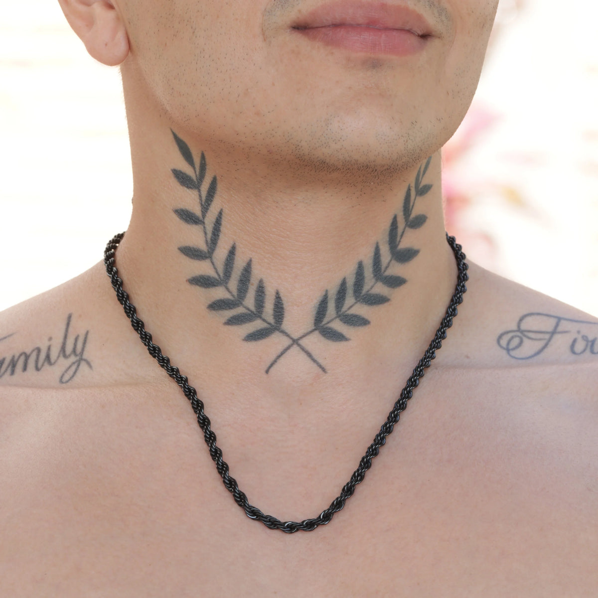 Tattoo of crossed laurel branches on a person’s neck and upper chest.