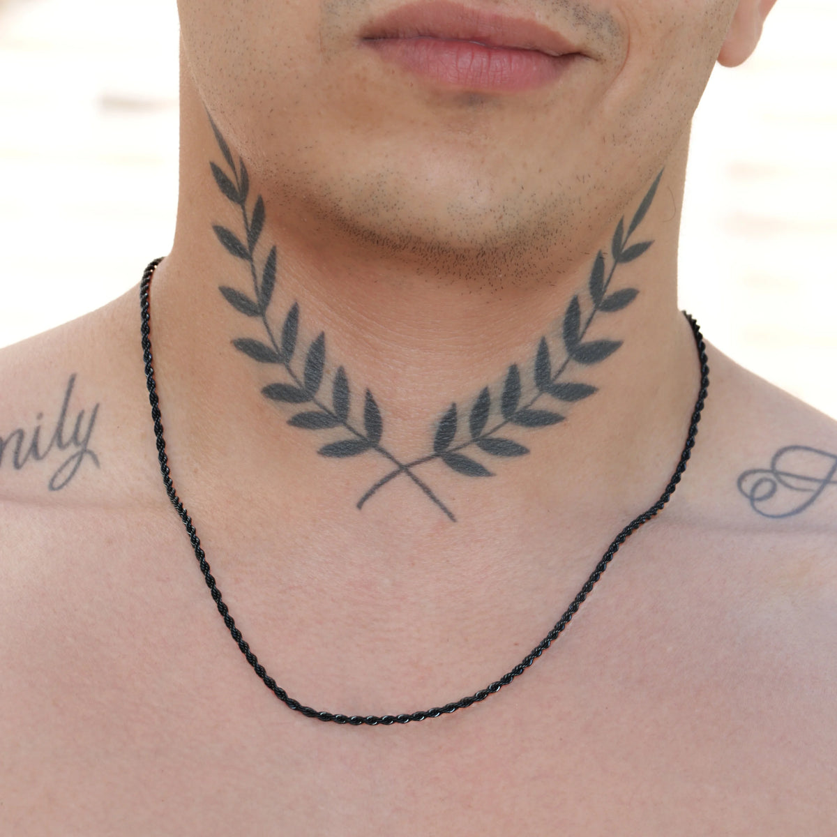 Tattoo of crossed olive branches on a person’s neck and upper chest.