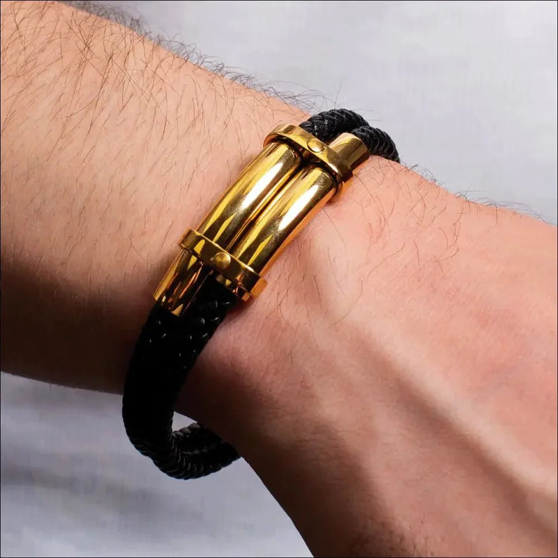 Gold-accented black cord bracelet worn on a wrist.