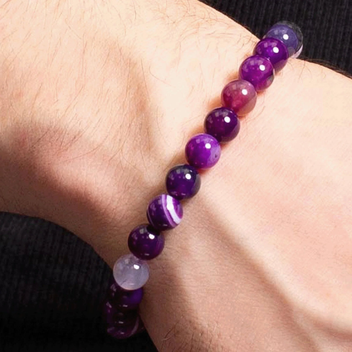 Purple gemstone bead bracelet worn on a wrist.