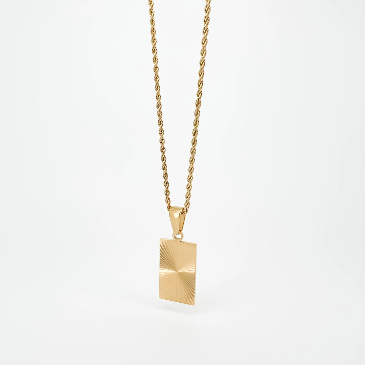 Gold pendant necklace with a rectangular charm featuring a sunburst pattern.