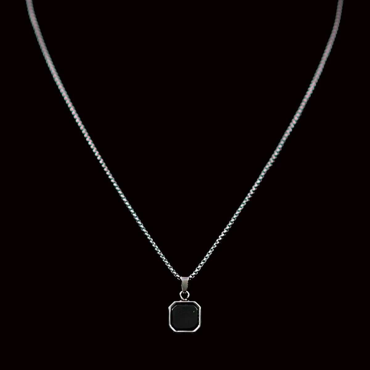 Silver necklace with a square black pendant.