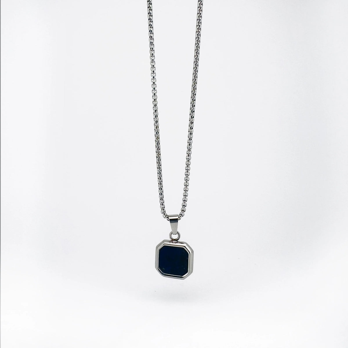 Silver necklace with a square black pendant.