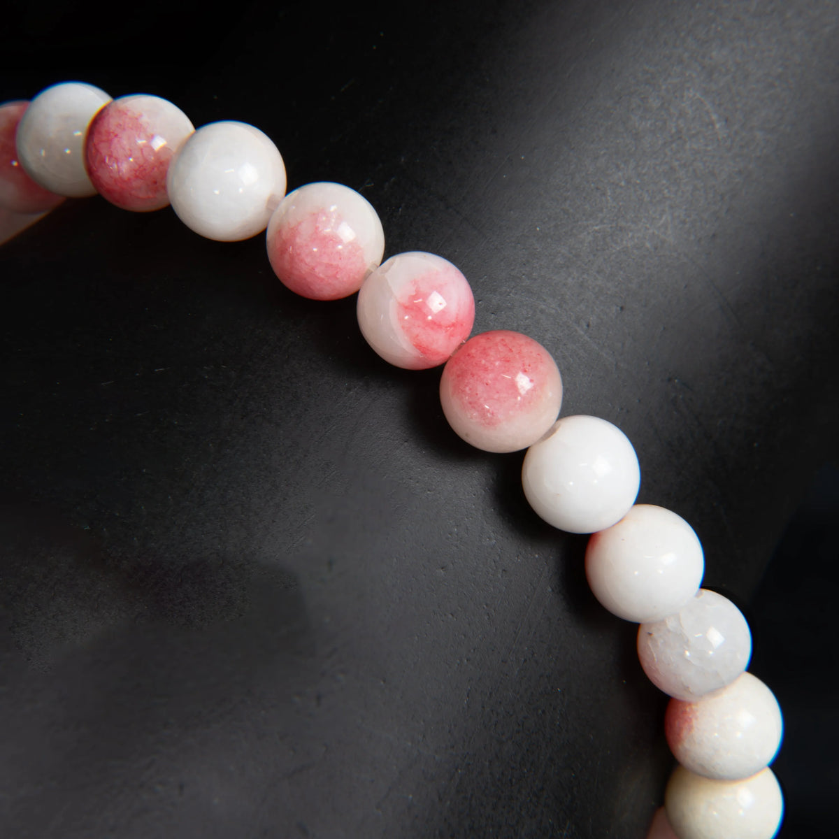 String of round beads alternating between white and pink-tinged colors.