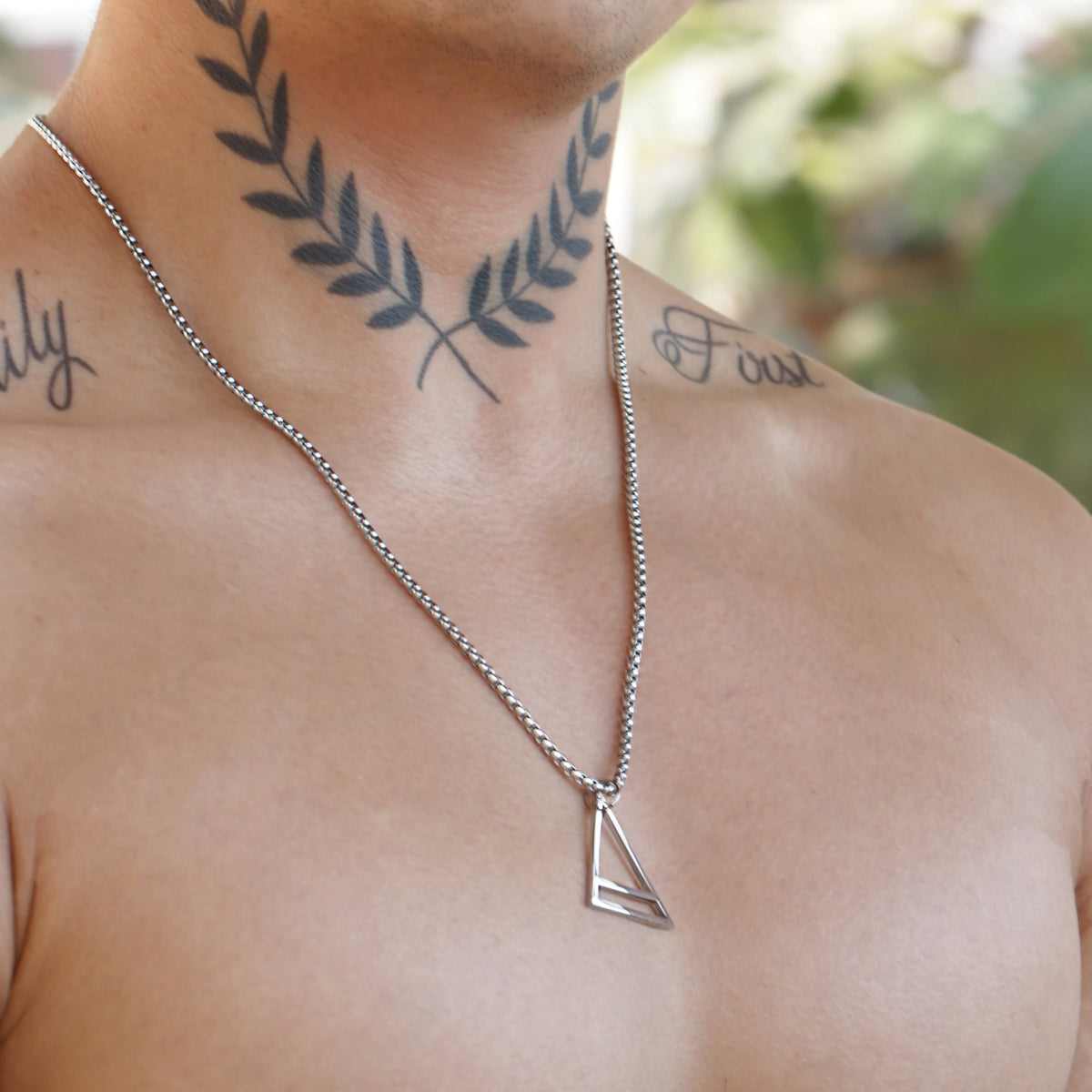 Silver triangular pendant on a chain necklace.