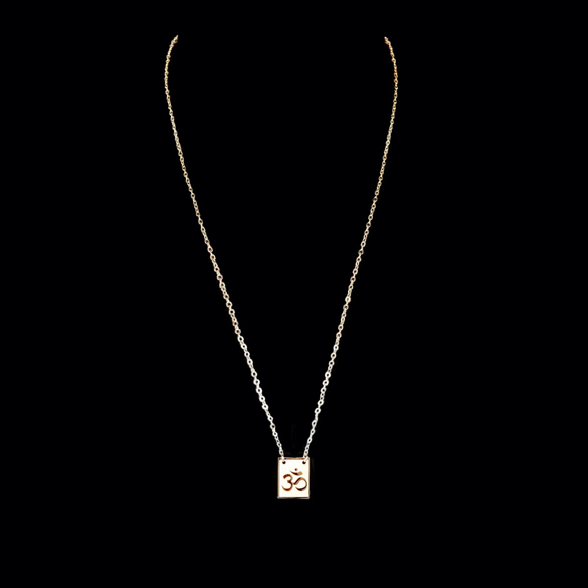 Gold chain necklace with a square pendant.