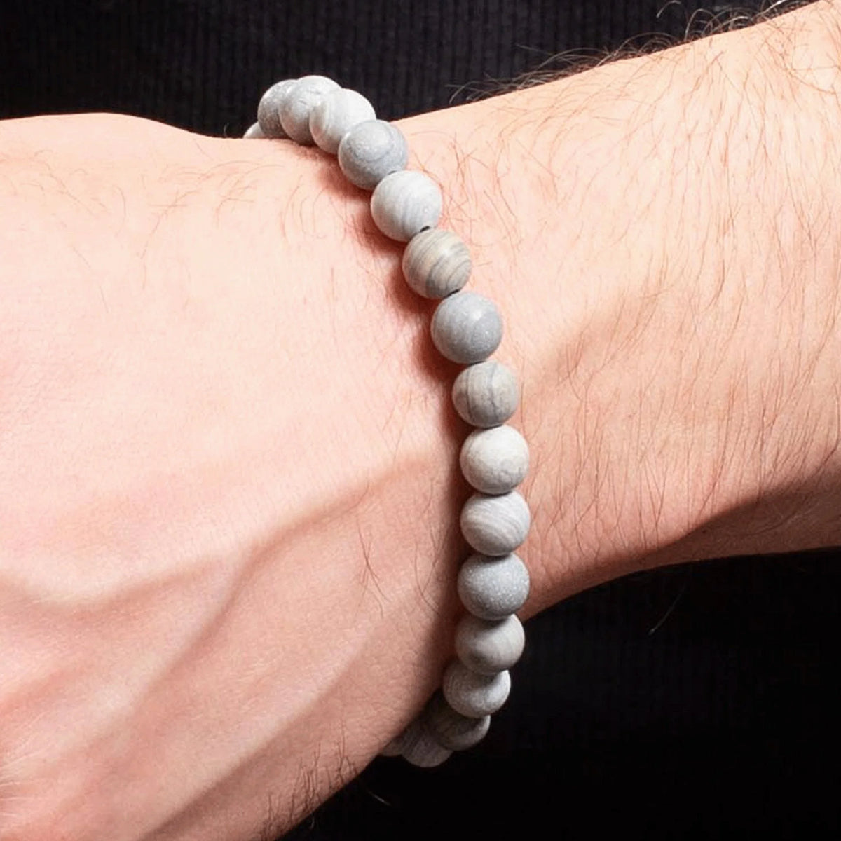 Beaded bracelet made of light-colored stone or mineral worn on a wrist.