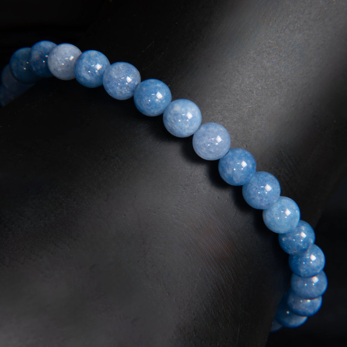 String of light blue, polished spherical beads forming a curved line.