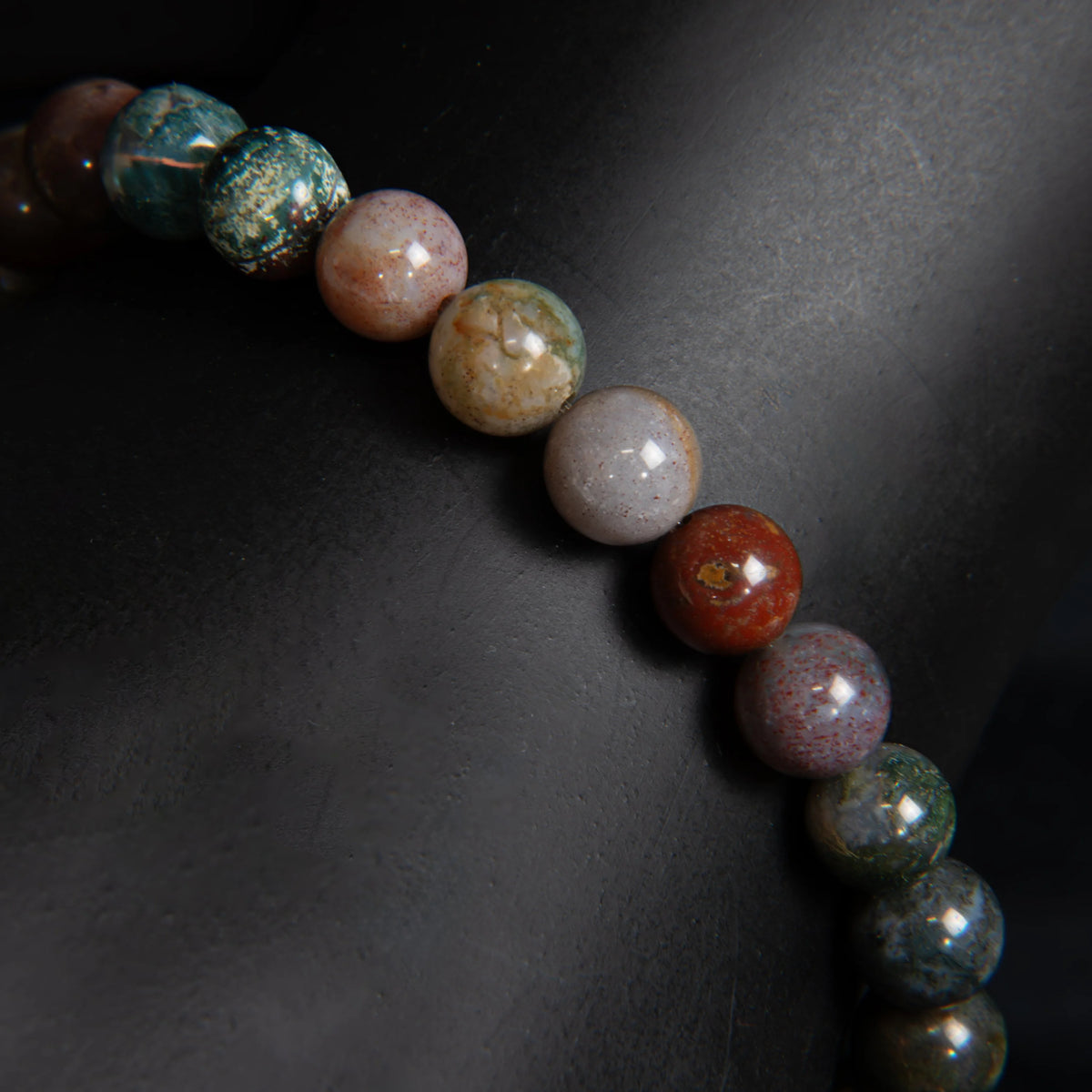 String of colorful polished stone beads in various earthy hues.