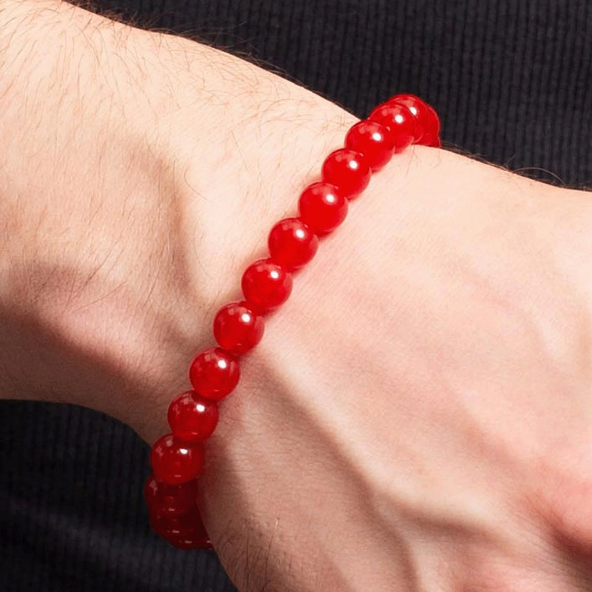 Red beaded bracelet worn on a wrist.