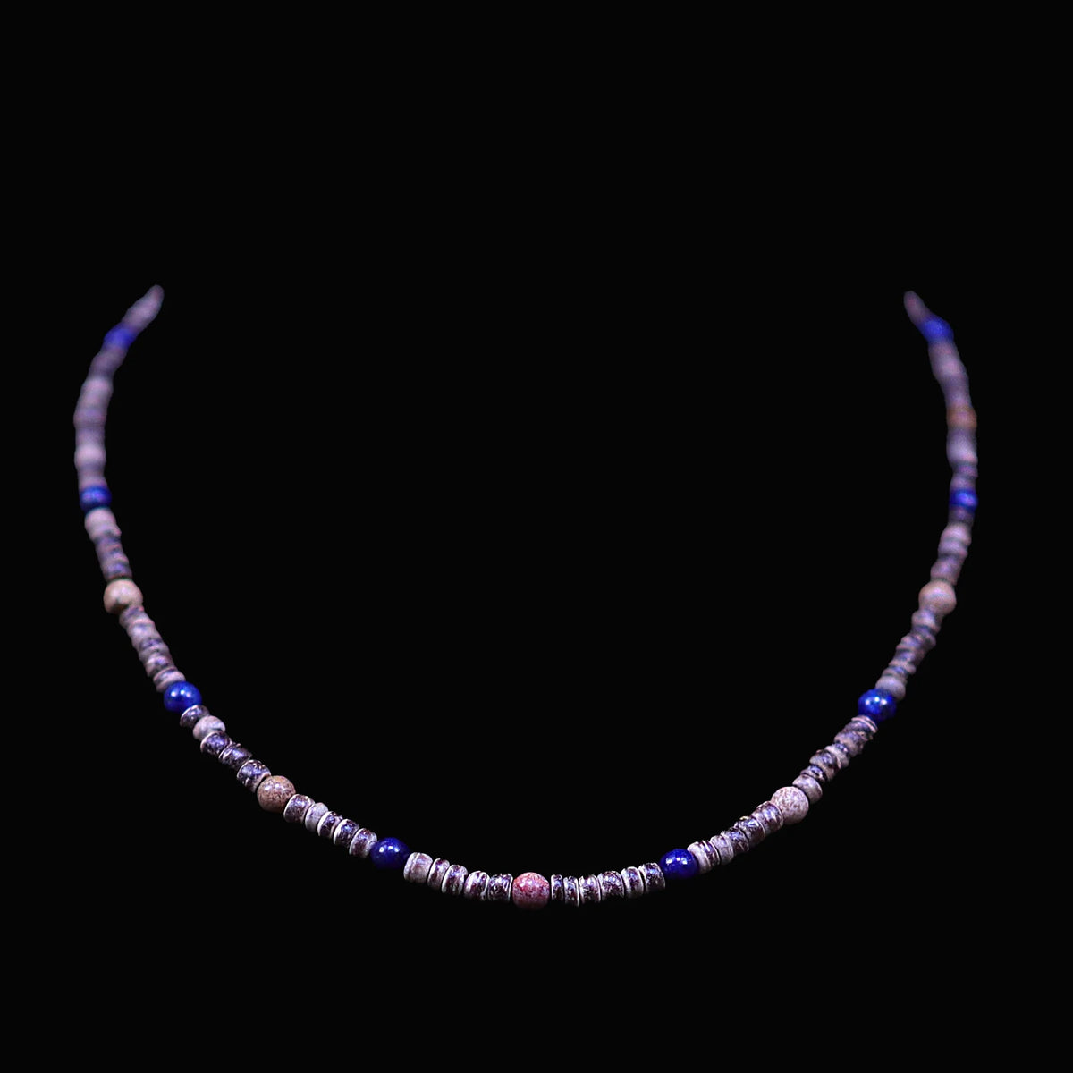 Beaded necklace with purple, blue, and pink stones on a black background.