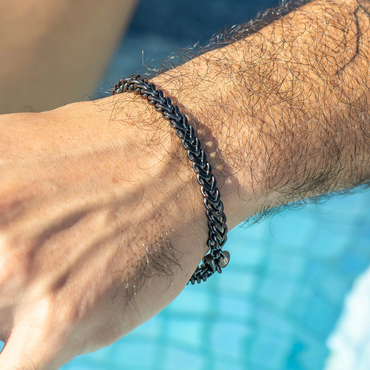 Black braided metal bracelet worn on a wrist.