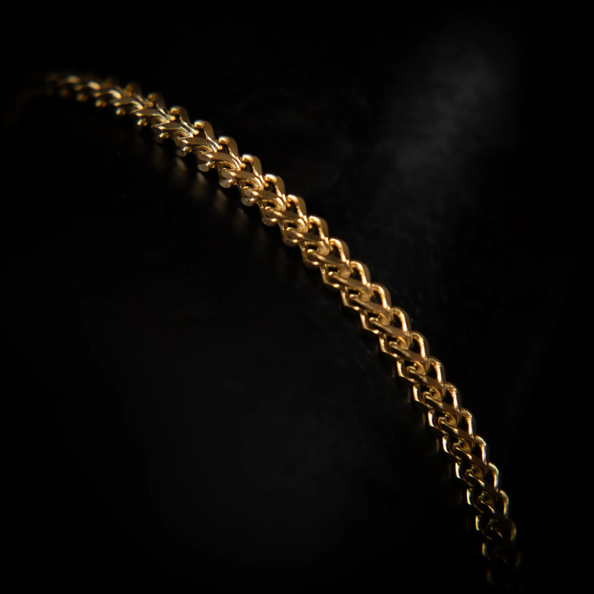 Gold chain with interlocking links against a dark background.