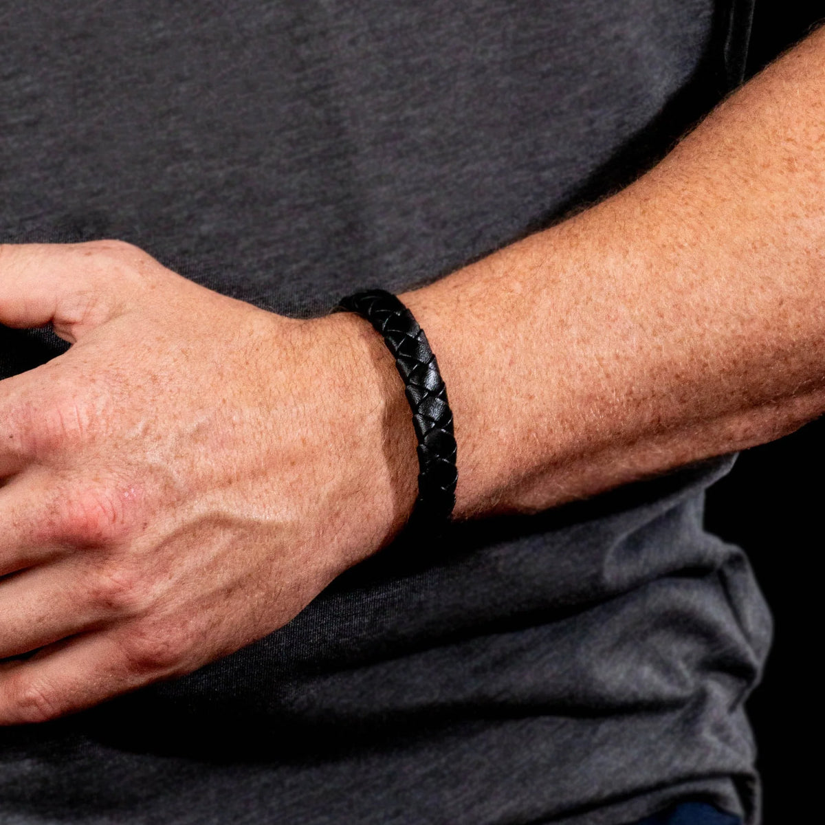 Black braided leather bracelet worn on a wrist.