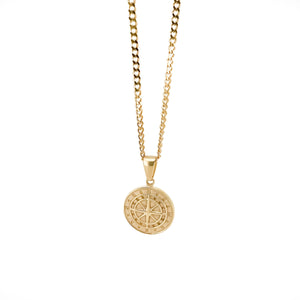 Gold pendant necklace featuring a circular medallion with a compass rose design.