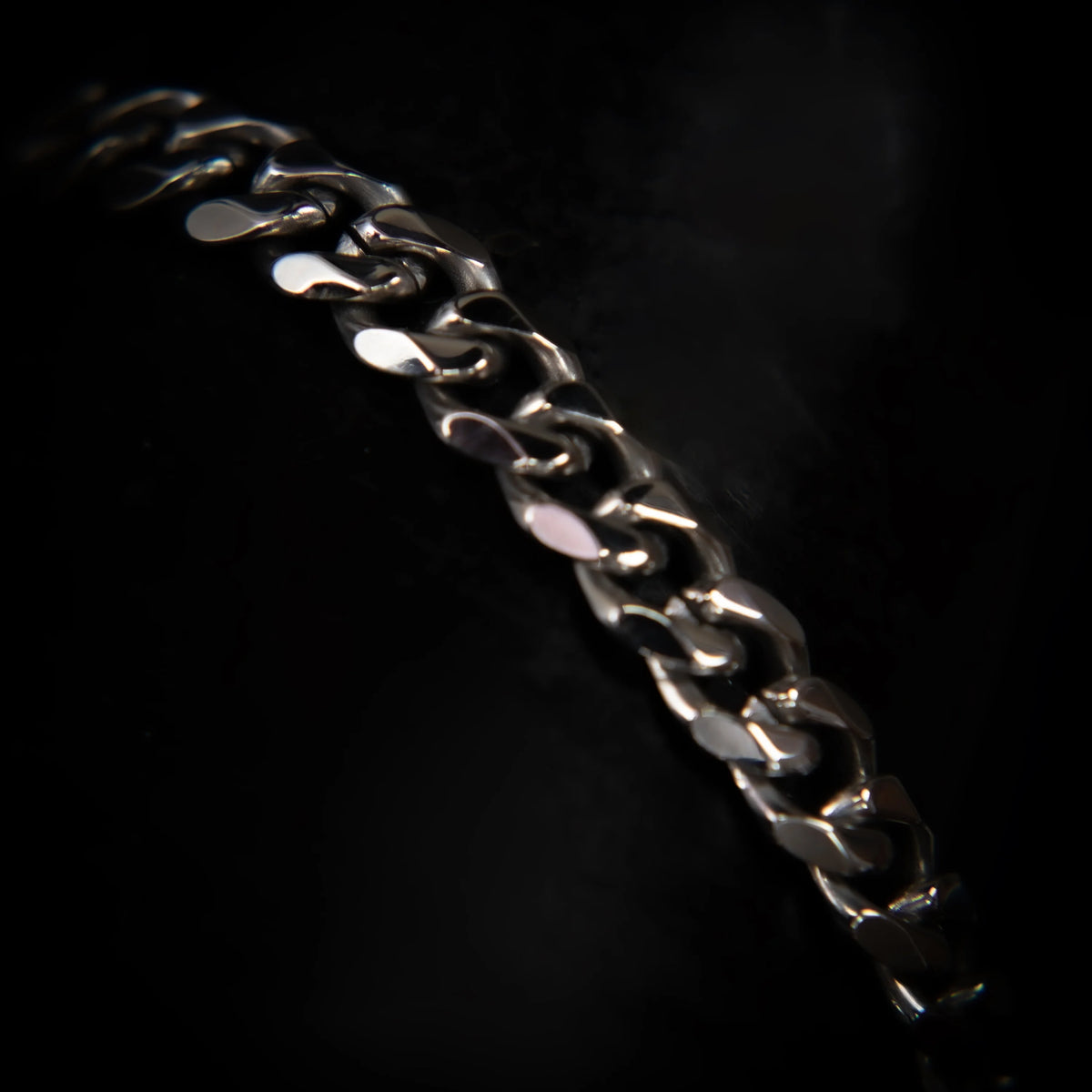 Metallic chain with interlocking links reflecting light against a dark background.