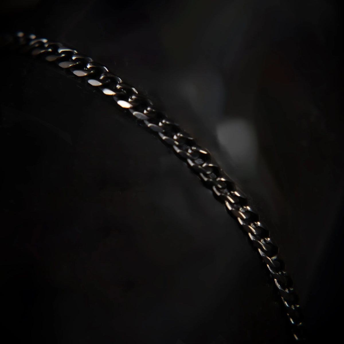 Metallic chain curving diagonally across a dark background.