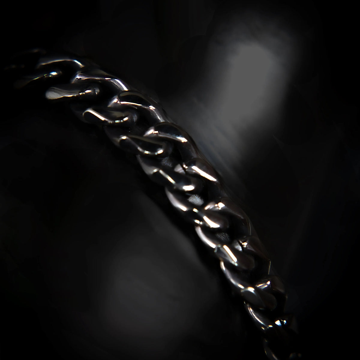 Shiny metal chain with interlocking links against a dark background.