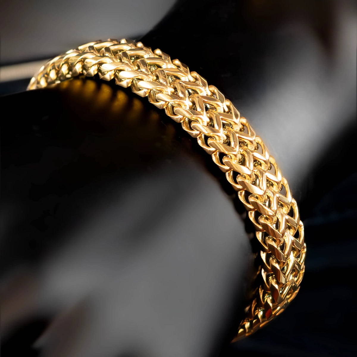 Gold chain bracelet with an intricate woven pattern.