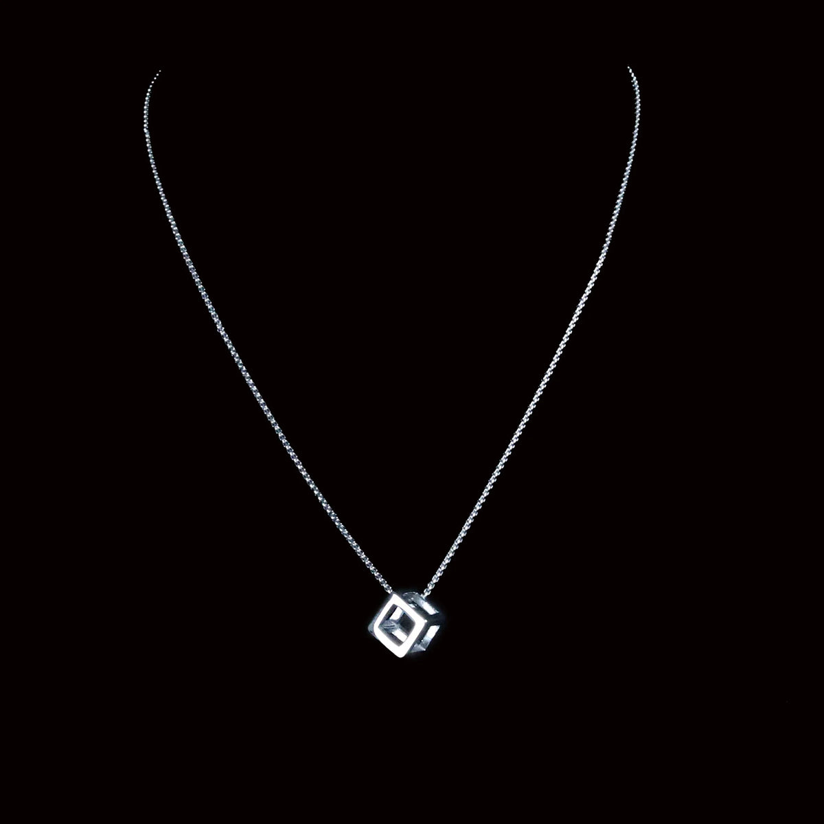 Silver necklace with a cube-shaped pendant.