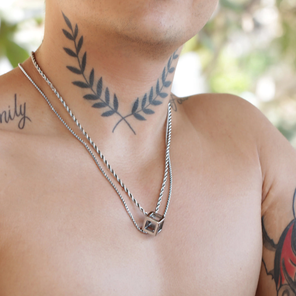 Tattoo of crossed laurel branches on a person’s neck and upper chest.