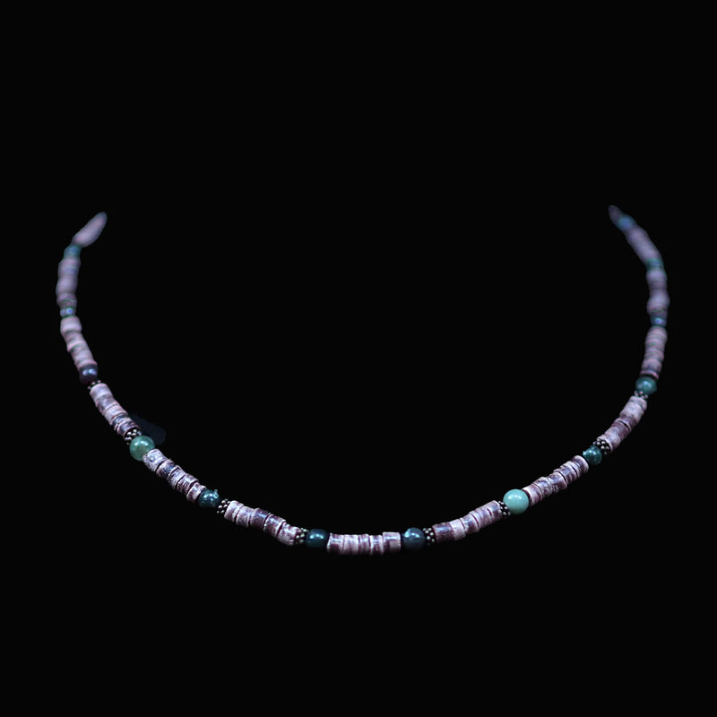 Delicate beaded necklace with turquoise and white beads on a black background.