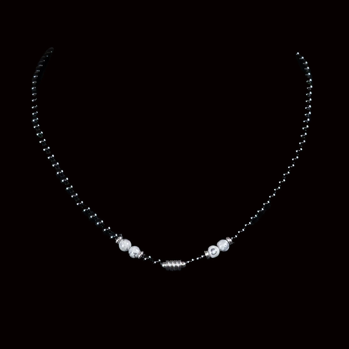 Delicate necklace with black beads and white pearls on a central pendant.