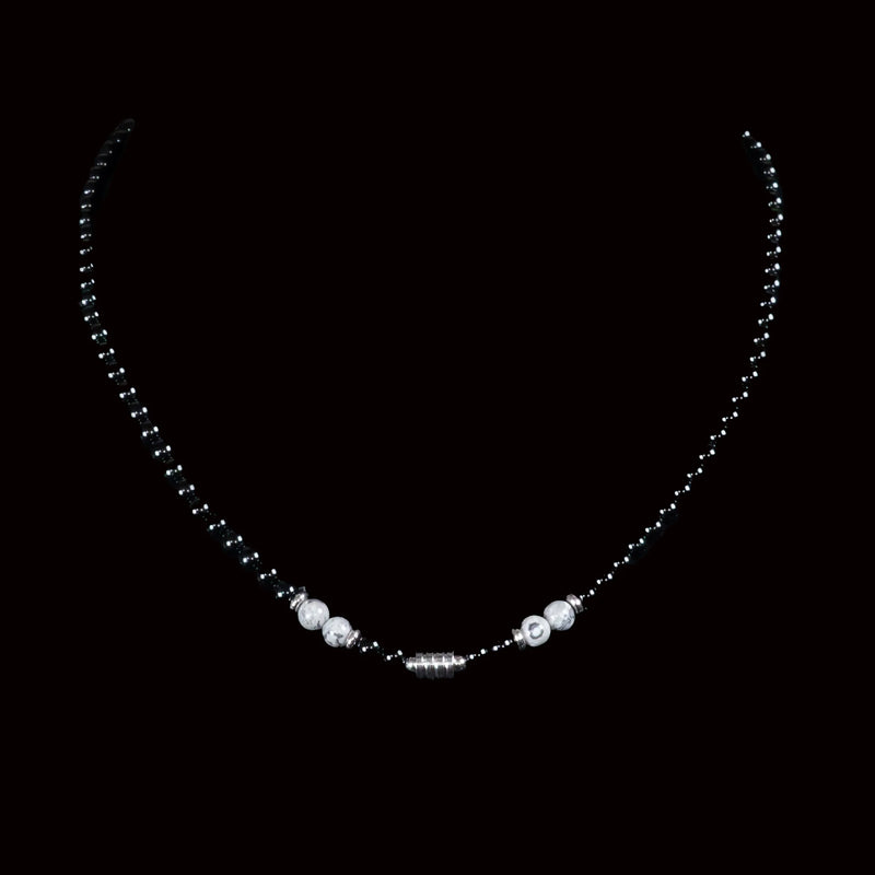 Delicate necklace with black beads and white pearls on a central pendant.