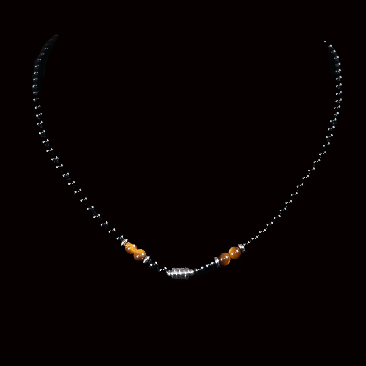 Delicate necklace with black beads and small gold and silver accents.