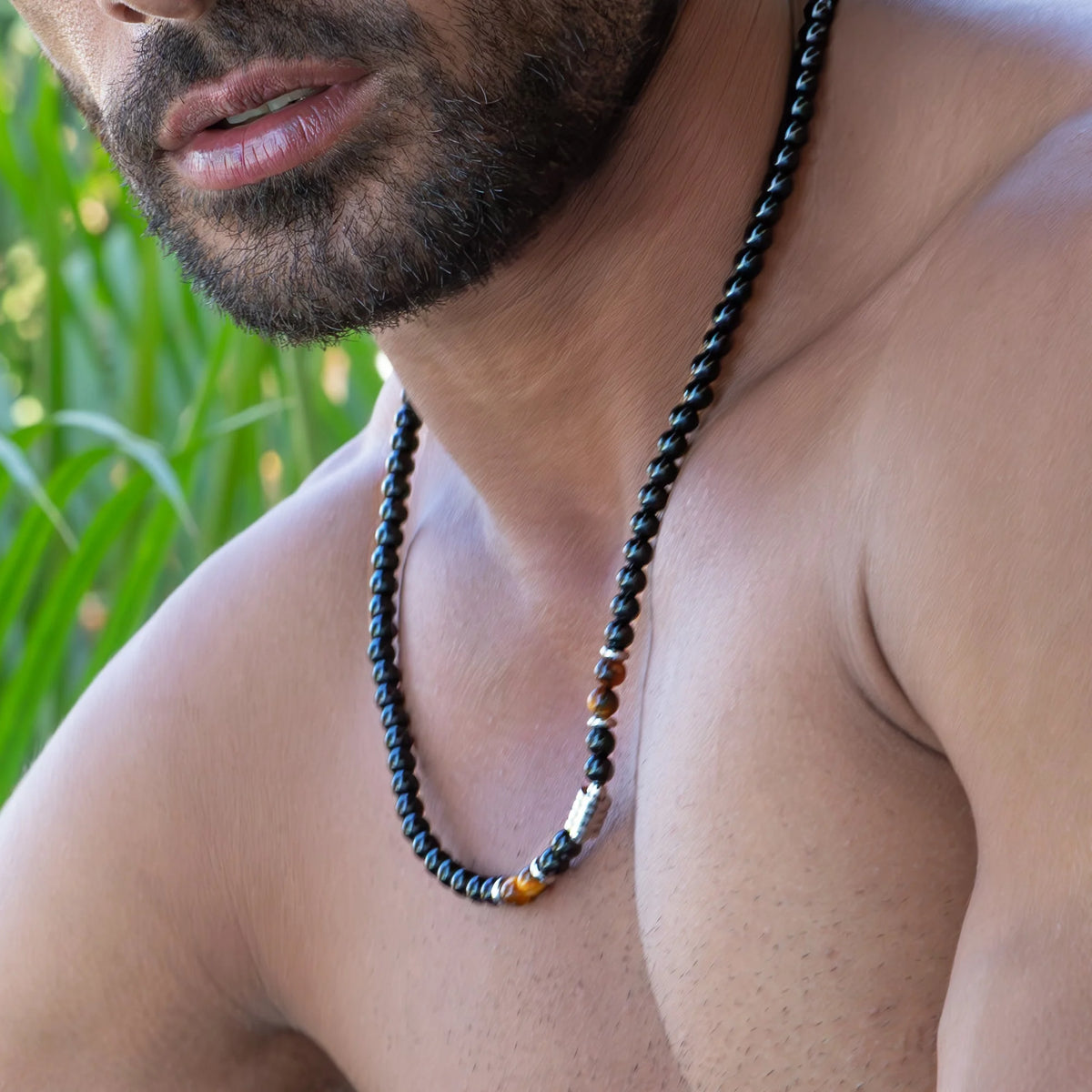 Beaded necklace with black and colorful stones worn by a person with facial hair.