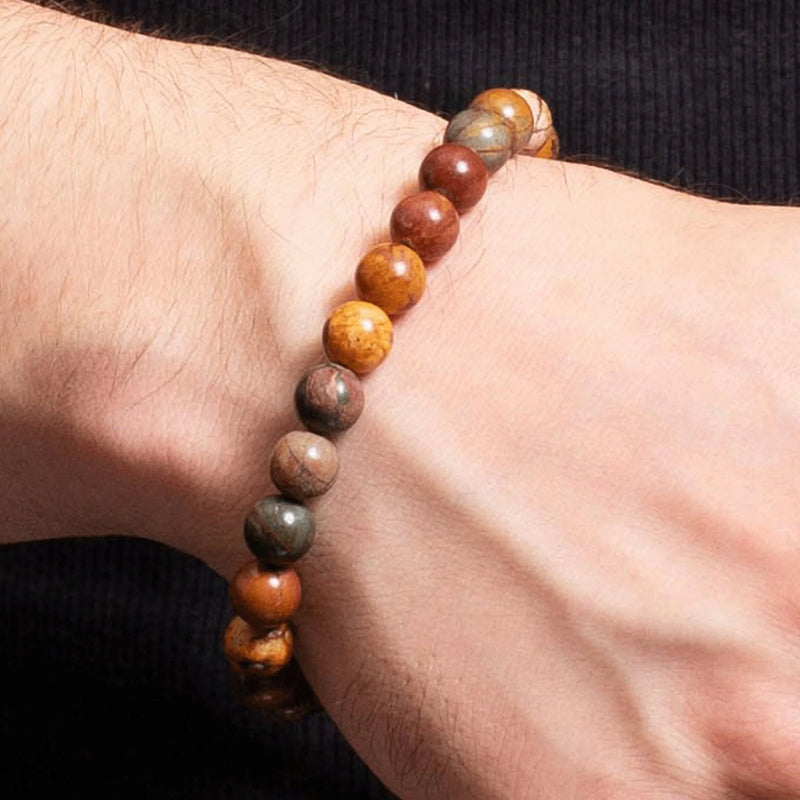 Beaded bracelet with multicolored stone or wooden beads worn on a wrist.