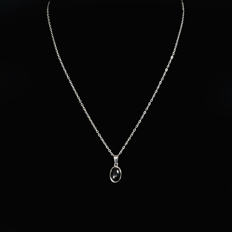 Silver necklace with an oval pendant containing a dark gemstone.