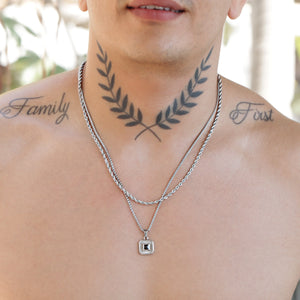 Tattoo of crossed olive branches on a person’s upper chest and neck.