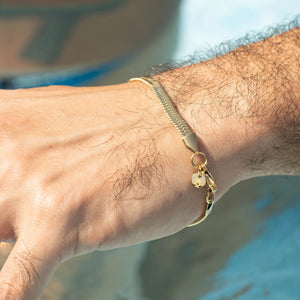 Gold chain bracelet with a small charm or pendant attached.