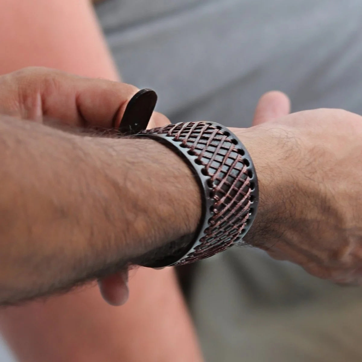 Latticed metal bracelet or cuff worn on a wrist.