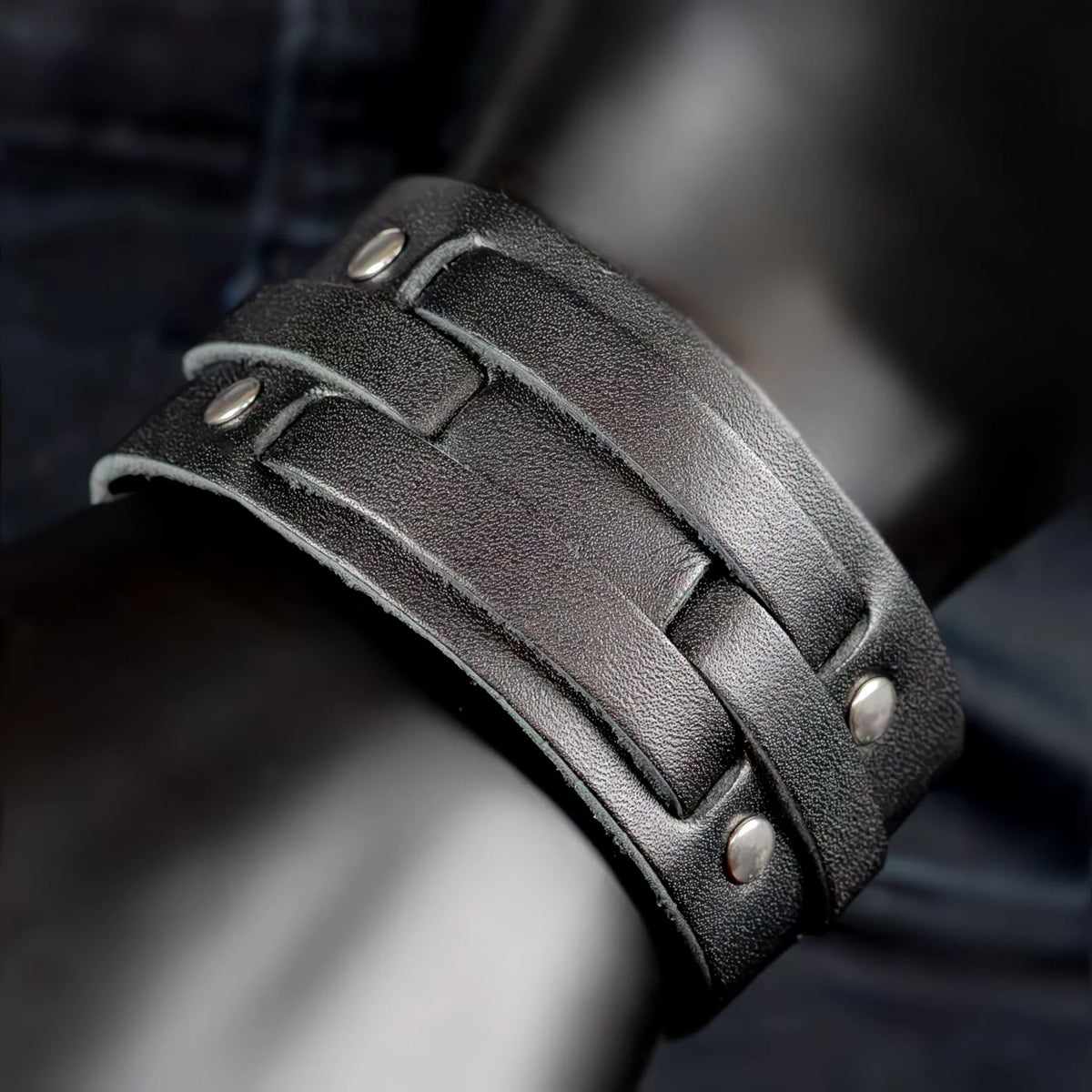 Black leather cuff bracelet with metal studs and straps.